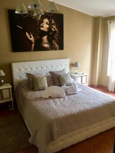a bedroom with a white bed with a painting on the wall at Chic 'N Charme Trastevere Terrace in Rome