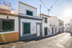 豐沙爾的住宿－Old Town House Madeira，一条街道,有一些绿色百叶窗的建筑