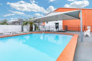 a swimming pool with a large umbrella next to a building at Howard Johnson by Wyndham Near Schlitterbahn in New Braunfels