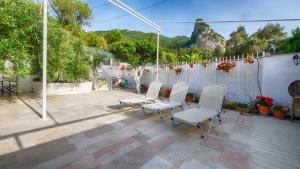 eine Terrasse mit weißen Stühlen, einem Zaun und einem Zaun in der Unterkunft Feakia apartment 2 in Agios Gordios