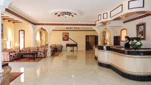 a woman standing at a reception desk in a lobby at Hôtel Relais Saiss in Sefrou