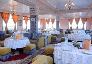 um salão de banquetes com mesas brancas e cadeiras amarelas em Hôtel Relais Saiss em Sefrou