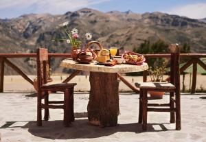 a table with food on top of a tree stump with two chairs at Colca Trek Lodge best experience in Pinchollo