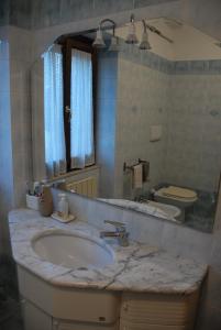 ein Badezimmer mit einem Waschbecken, einem Spiegel und einem WC in der Unterkunft Fattoria Nonno Neno B&B in Appignano