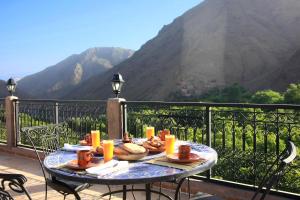 a table with food on top of a balcony with a mountain at Kasbah Imoula in Imlil
