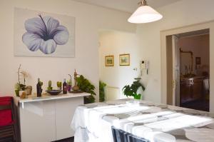 una sala da pranzo con tavolo e un dipinto di fiori sul muro di Casa Alcalà Deluxe a Catania Altre 75 foto