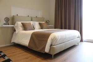 una camera da letto con un grande letto con lenzuola e cuscini bianchi di The sisters a Castelsardo