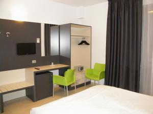 una camera d'albergo con scrivania e sedie verdi di Althea Palace Hotel a Castelvetrano Selinunte