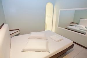 Dieses weiße Zimmer verfügt über einen Spiegel und ein Surfbrett. in der Unterkunft MOTEL 3 PEIXINHOS (Adults Only) in Blumenau