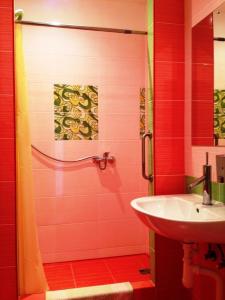 een rode badkamer met een wastafel en een douche bij Motel Golden Fox in Zeļčava