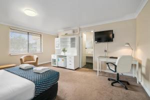 a hotel room with a bed and a desk and a computer at Garden City Motor Inn in Wagga Wagga