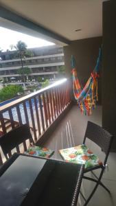 a balcony with a hammock and a table and chairs at Muro Alto Malawi Beach Dream in Porto De Galinhas