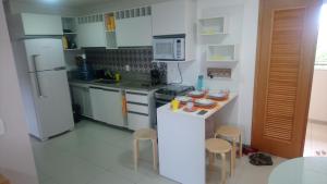 a kitchen with white appliances and a counter with stools at Muro Alto Malawi Beach Dream in Porto De Galinhas