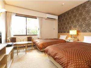a hotel room with two beds and a window at Kyukamura Noto-Chirihama in Hakui