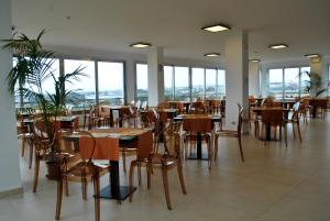 un comedor con mesas, sillas y ventanas en Althea Palace Hotel, en Castelvetrano Selinunte