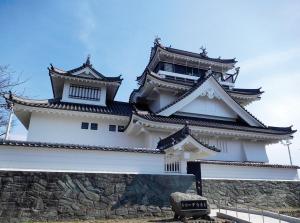 a large white building with two towers on a stone wall at Hotel Trend Okazaki Ekimae in Okazaki