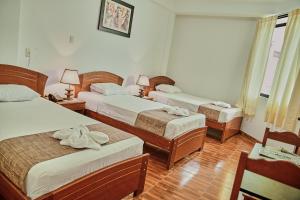 a hotel room with three beds with towels on them at Hotel sueño Tropical in Tarapoto