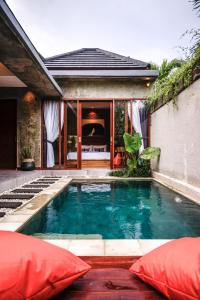 ein Swimmingpool mit roten Kissen vor einem Haus in der Unterkunft La Isla Villas Bali in Canggu