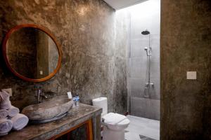 a bathroom with a sink and a toilet and a mirror at La Isla Villas Bali in Canggu
