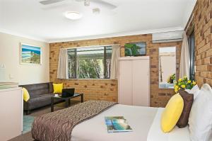 1 dormitorio con cama y pared de ladrillo en Byron Bayside Central Studio Apartments, en Byron Bay