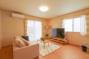 a living room with a couch and a flat screen tv at Hyakuna Terrace in Nanjo