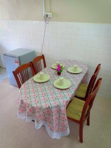 a table with two plates and a vase of flowers on it at Homestay Sejati in Kuala Berang