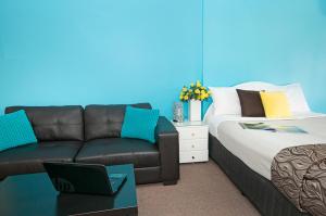 a living room filled with furniture and a blue couch at Byron Bayside Central Studio Apartments in Byron Bay
