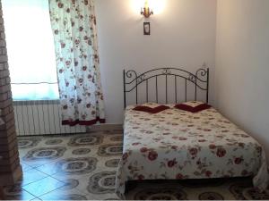 um quarto com uma cama com colcha floral e uma janela em Pod akacjami em Baligród
