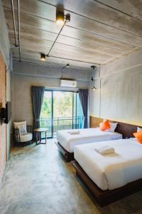 a hotel room with two beds and a balcony at Mosstel in Phitsanulok