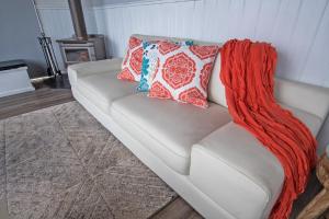 a white couch with two colorful pillows on it at Stunning Waterfront only 10 minutes to Phillip Island - FREE EV UNIT 7kW for electric cars - pet friendly, fireplace FREE WIFI wine & chocolates in Kilcunda