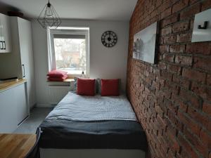 een slaapkamer met een bakstenen muur en een bed met kussens bij theApartments Manufaktura in Łódź