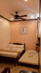 two beds in a room with a ceiling fan at Dumdum Medical Plaza and Residences in Toledo City