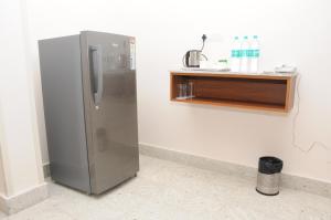 a stainless steel refrigerator in a kitchen with a shelf at Sreeparthi Hotel in Puttaparthi