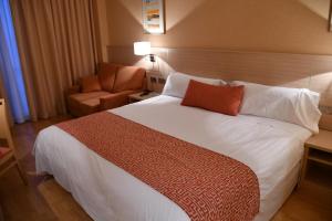 una habitación de hotel con una gran cama blanca y una silla en Hotel Class Valls, en Valls
