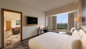 a hotel room with a bed and a large window at Novotel Hyderabad Convention Centre in Hyderabad