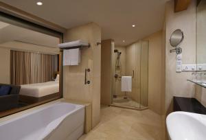 a bathroom with a tub and a bed and a shower at Novotel Hyderabad Convention Centre in Hyderabad