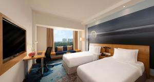 a hotel room with two beds and a desk and a tv at Novotel Hyderabad Convention Centre in Hyderabad