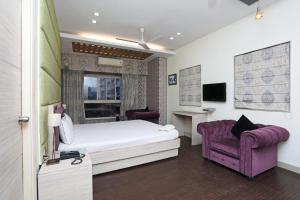 a bedroom with a bed and a purple chair at Hotel Rushabh Home in Kolkata +71 photos