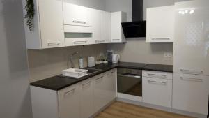 una cocina con armarios blancos y fregadero en Apartament Marzenie 6 - Opole en Opole