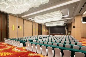 une salle de conférence vide avec des chaises blanches et un écran dans l'établissement Ramada Wyndham Zhengzhou Xinzheng, à Xinzheng