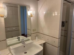W białej łazience znajduje się umywalka i lustro. w obiekcie Palù vacanze: Cuore del centro storico w Aoście