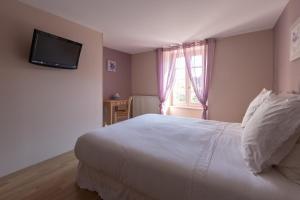 a bedroom with a white bed and a television on the wall at Les Voyageurs in Saint-Martin-la-Méanne