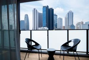 2 stoelen en een tafel in een kamer met een skyline van de stad bij Oakwood Apartments Nishi-Shinjuku in Tokyo