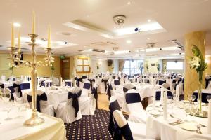una sala de banquetes con mesas y sillas blancas en una habitación en Tara Hotel en Killybegs