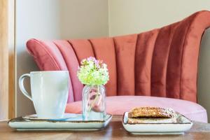 - une table avec une tasse de café et un vase de fleurs dans l'établissement Hotel des Iris, à Auvers-sur-Oise