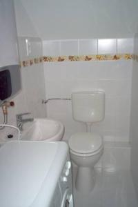 a white bathroom with a toilet and a sink at Rebeka Villa in Zamárdi