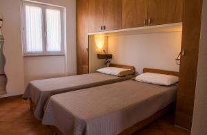 deux lits dans une petite pièce avec une fenêtre dans l'établissement GF Apartments Li Seddi, à Badesi 153 autres photos