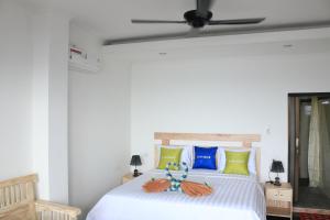 1 dormitorio con 1 cama blanca y ventilador de techo en Alur Beach Homestay, en Amed