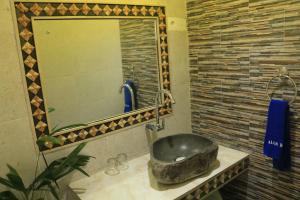 een badkamer met een wastafel en een grote spiegel bij Alur Beach Homestay in Amed