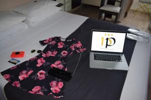 Una cama con un vestido y un ordenador portátil. en Hotel Perugino en Milán